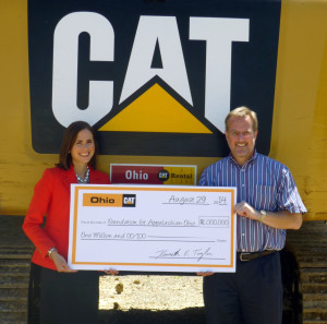 Ken Taylor presents a $1 million check to Cara Dingus Brook, FAO president and CEO, standing in front of an Ohio CAT sign.