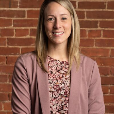Christina McLean is pictured standing in front of a brick wall.